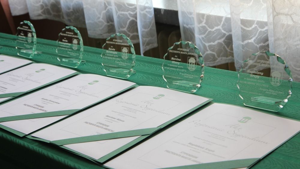 Listy gratulacyjne i szklane statuetki ułożone na stole