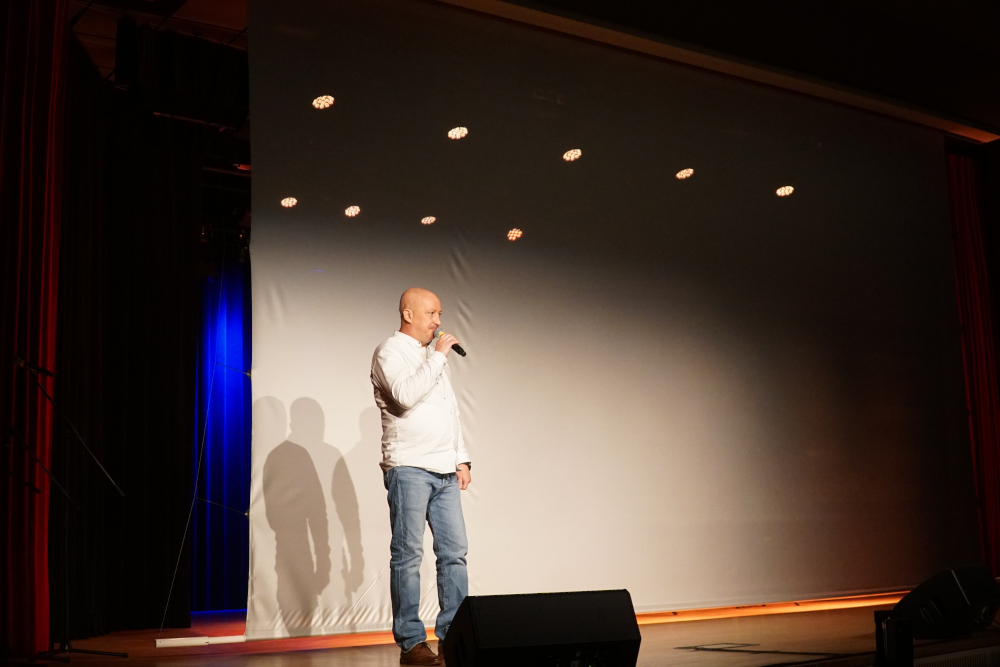 Mężczyzna przemawiający do mikrofonu na scenie