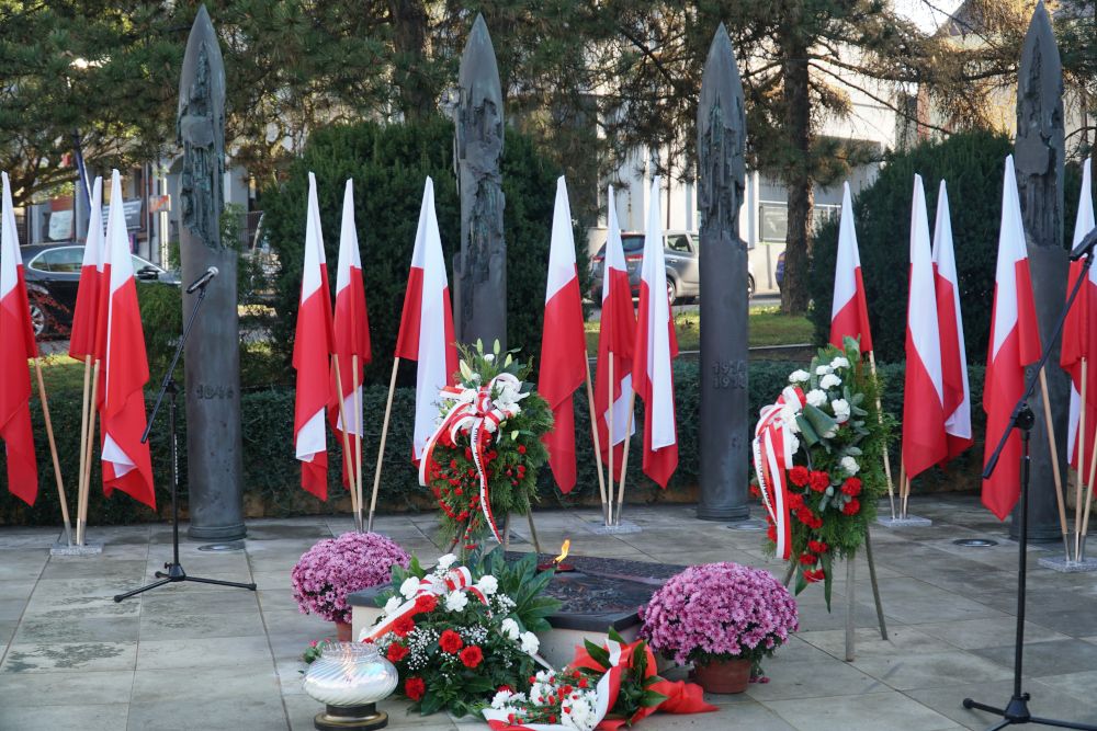 Pomnik niepodległości przyozdobiony biało-czerwonymi flagami i kwiatami