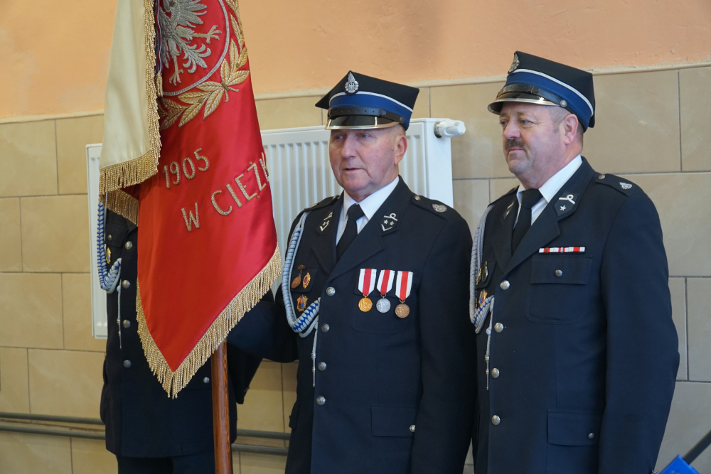 Dwóch mężczyzn w mundurach strażackich ze sztandarem