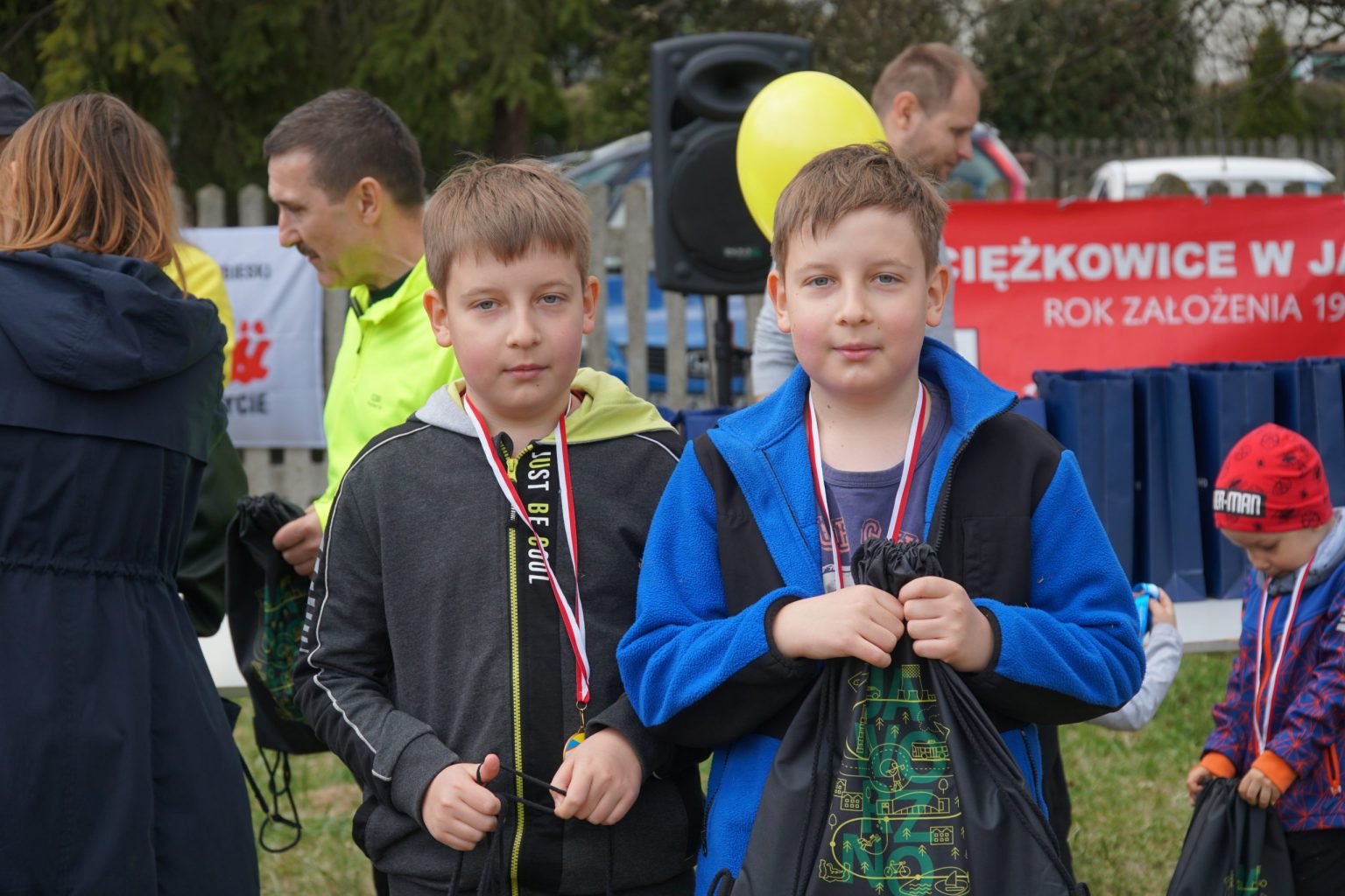 Dwóch chłopców z medalami na szyi trzyma w dłoniach nagrody