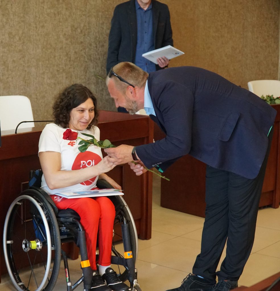 Mężczyzna wręcza różę kobiecie na wózku inwalidzkim