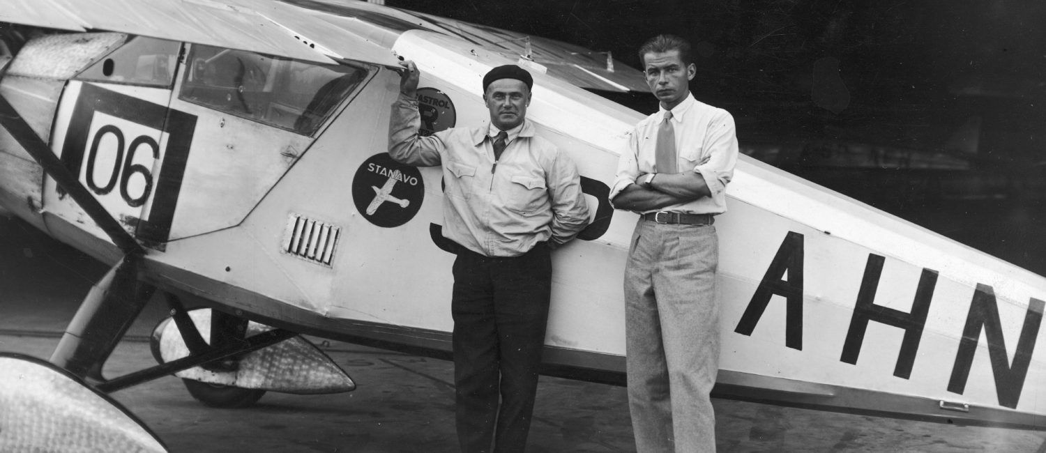 Dwóch mężczyzn stojących przed samolotem - zdjęcie czarno-białe