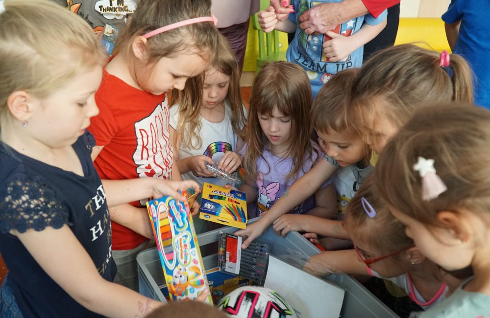 Grupa dzieci wyciągająca przybory z pudełka