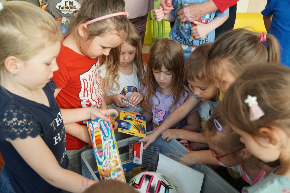 Grupa dzieci wyciągająca przybory z pudełka