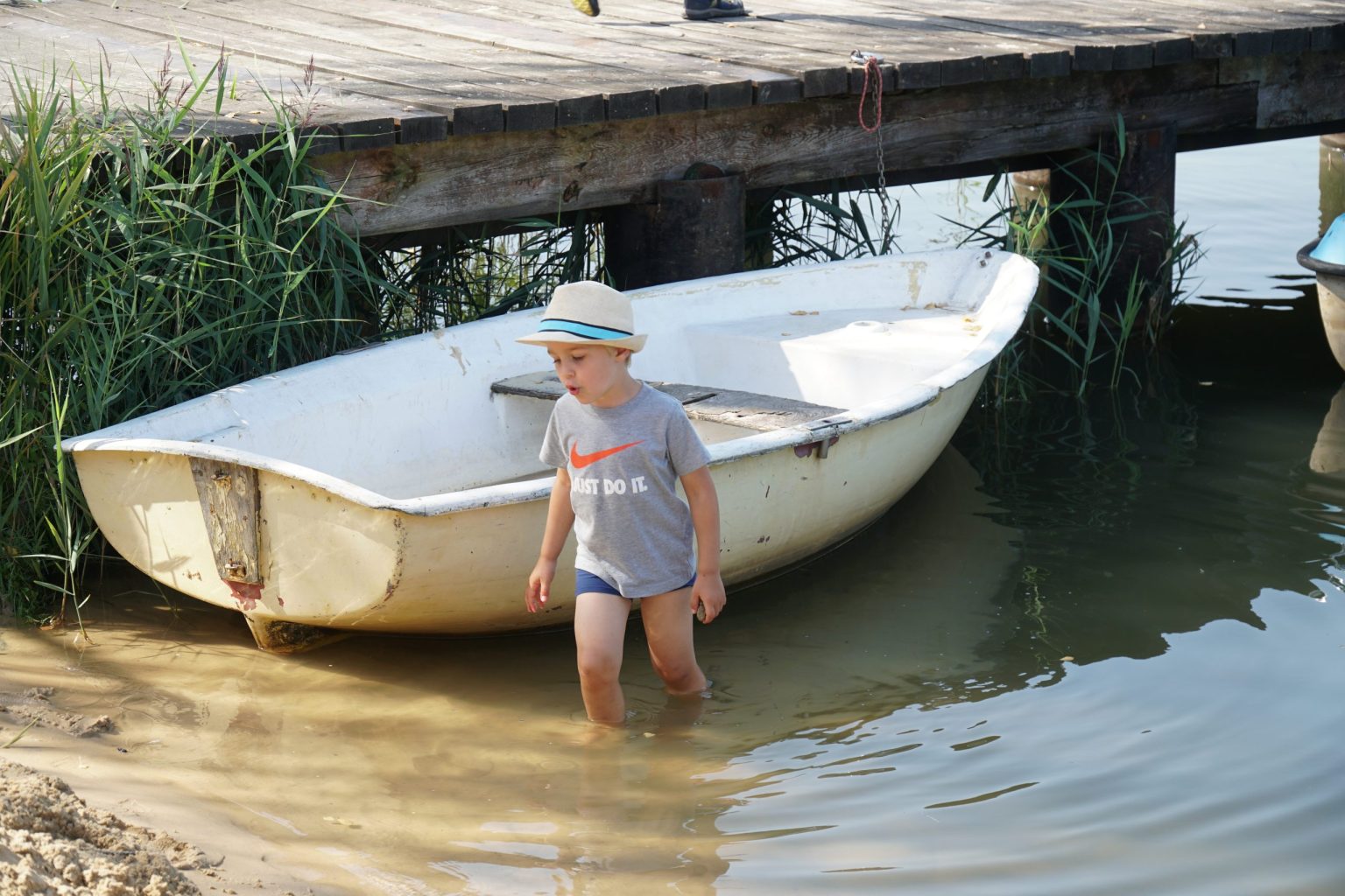 Chłopiec chodzi po wodzie w tle łódka