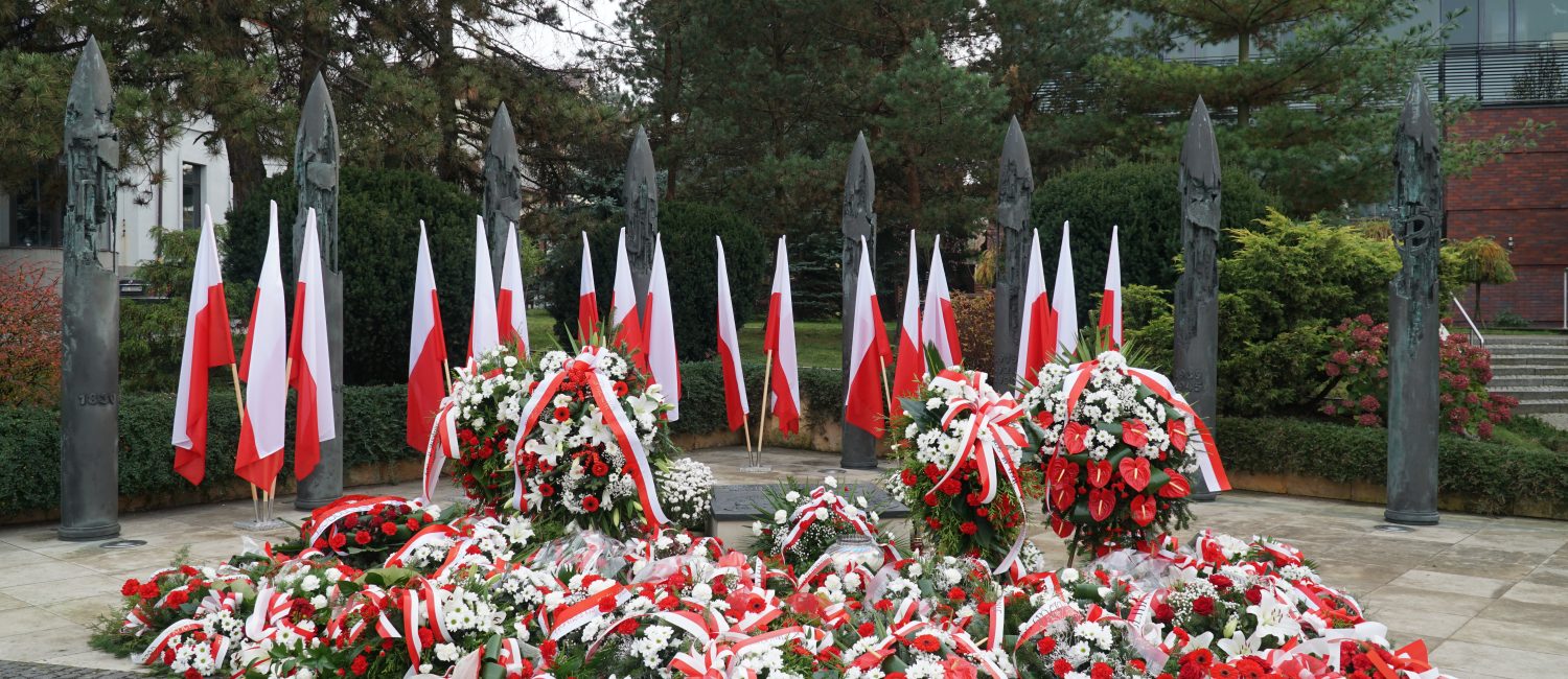 Biało-czerwone kwiaty leżące pod Pomnikiem Niepodległości