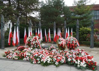 Biało-czerwone kwiaty leżące pod Pomnikiem Niepodległości