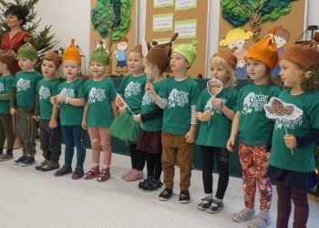 Grupa dzieci stojąca w rzędzie. Dzieci ubrane są w zielone koszulki