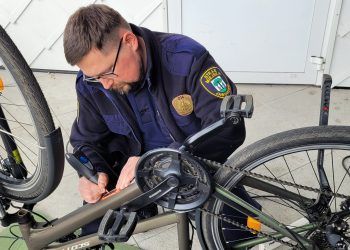 Mężczyzna w mundurze straży miejskiej podczas znakowania roweru