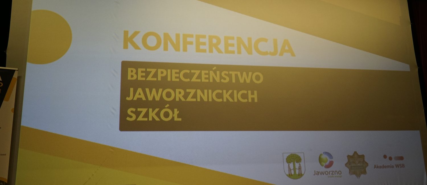 Slajd na dużym ekranie z napisem "Konferencja bezpieczeństwo jaworznickich szkół". Na ekranie widoczne są też loga Miasta Jaworzna, Policji i Akademii WSB.